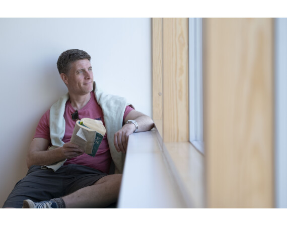 Male student reading by window at Anniesland Campus