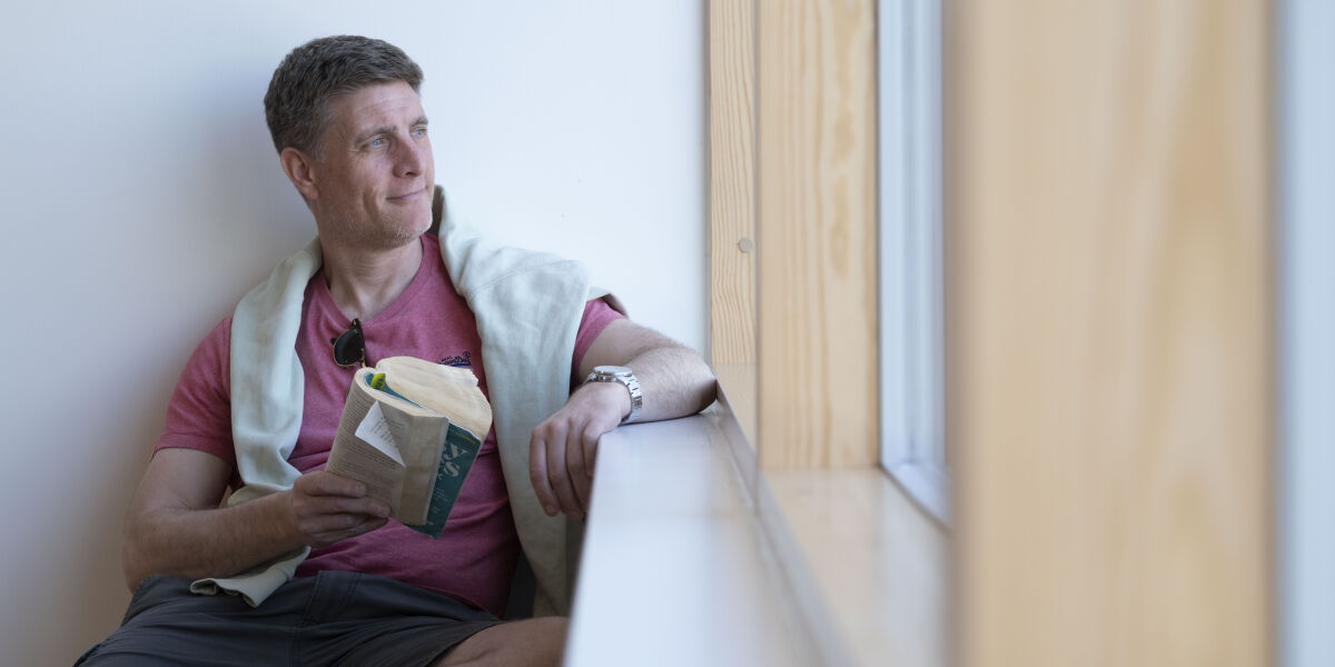 Male student reading by window at Anniesland Campus