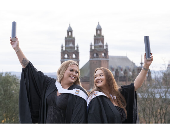 Two female graduates holding their scrolls