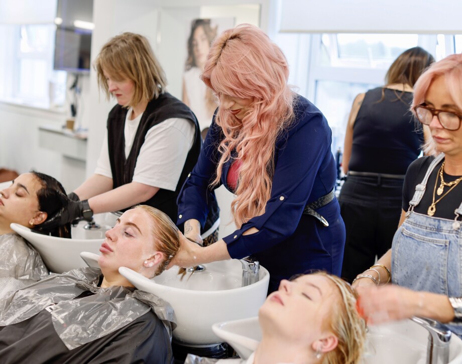 Three models getting their hair washed after colouring by three hair stylists.